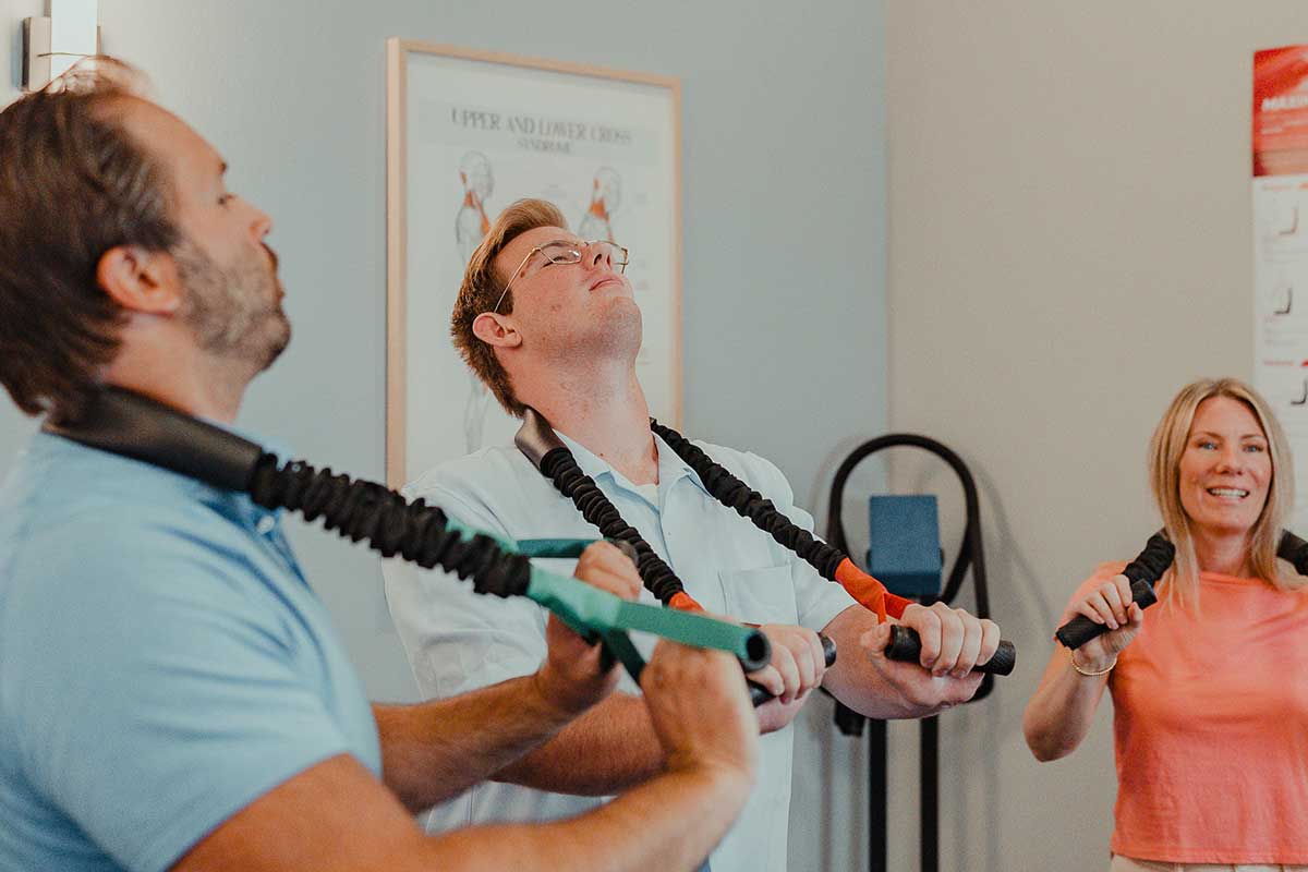 Dr. Cody Drake teaching two patients corrective exercises